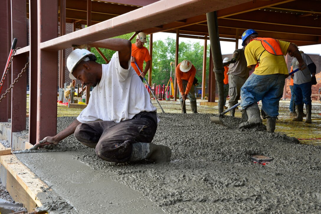 McGHEE TYSON AIR NATIONAL GUARD BASE, Tenn. -   A construction crew member smooths the edge of the concrete floor pad while other members pour and distribute around him here May 15, 2015. Crews started pouring the pad at 4 a.m. to allow the concrete time to set and cure more efficiently before the afternoon warmer temperatures. It will take 17 truckloads of cement to complete this pad on the ground floor of the classroom facility. The new TEC dormitory and classroom facility will contain approximately 47,000 square feet of additional space on three levels and two levels with ten 20-person and two 100-person classrooms, HD audio/visual capabilities, wireless capability, 97 single occupancy dorm rooms, energy efficient natural and led lighting, hearing and mobility accessible accommodations. (U.S. Air National Guard photo by Master Sgt. Jerry D. Harlan/Released)