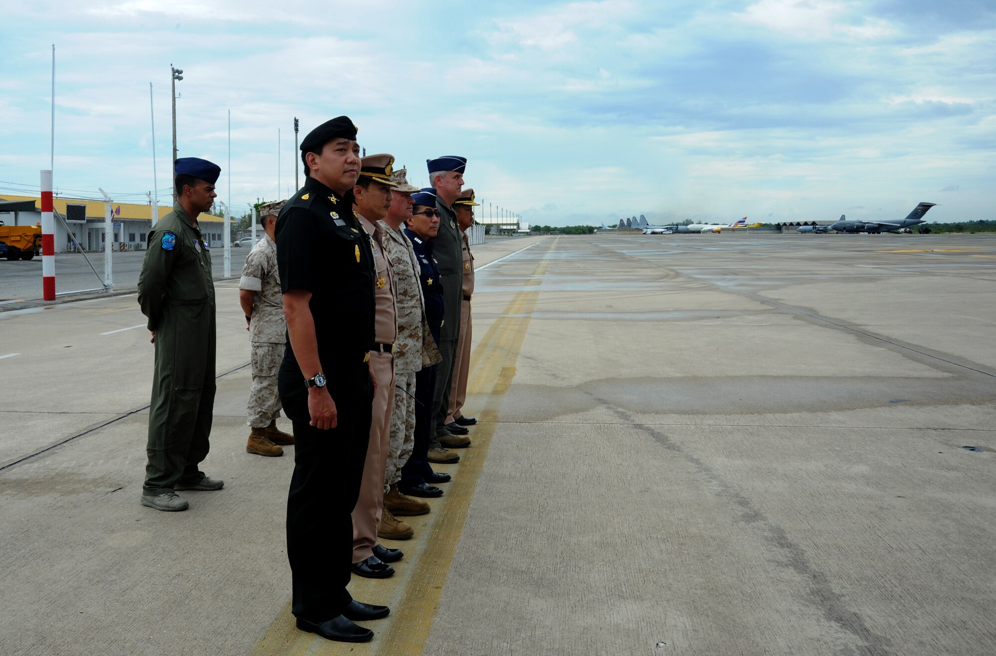U.S. military and Royal Thai Armed Forces members stand at attention in preparation to welcome W. Patrick Murphy, Chargé d’affaires of the U.S. Embassy in Thailand, during his visit to Utapao Royal Thai Naval Airfield, Thailand, May 14, 2015. Joint Task Force-505 designated Utapao an Intermediate Staging Base that ensures earthquake relief supplies and personnel flow in and out of Nepal. U.S. and Thai armed forces are working together at the ISB to coordinate humanitarian aid and disaster relief efforts for the government and people of Nepal. (U.S. Air Force photo by Staff Sgt. Alexander Martinez/Released)