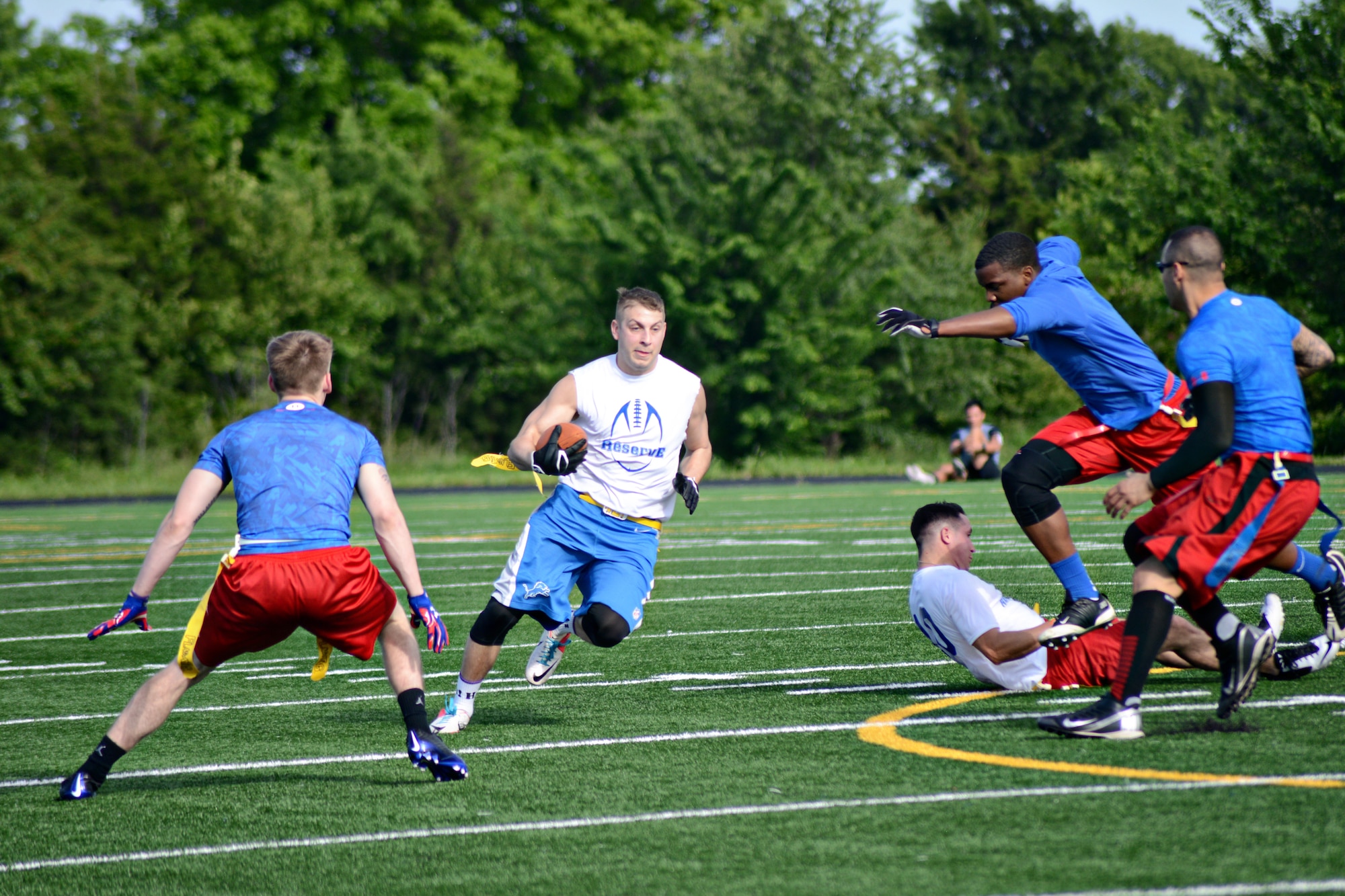 Reserve White’s Brett Nims tries to elude Med Group players Hunter Hessong, Kelton Eddins and Benito Lerma during their Tuesday night game. Both teams were previously undefeated going into the game where Reserve White shut out the Med Group 24-0. (Air Force photo by Kelly White/Released)
