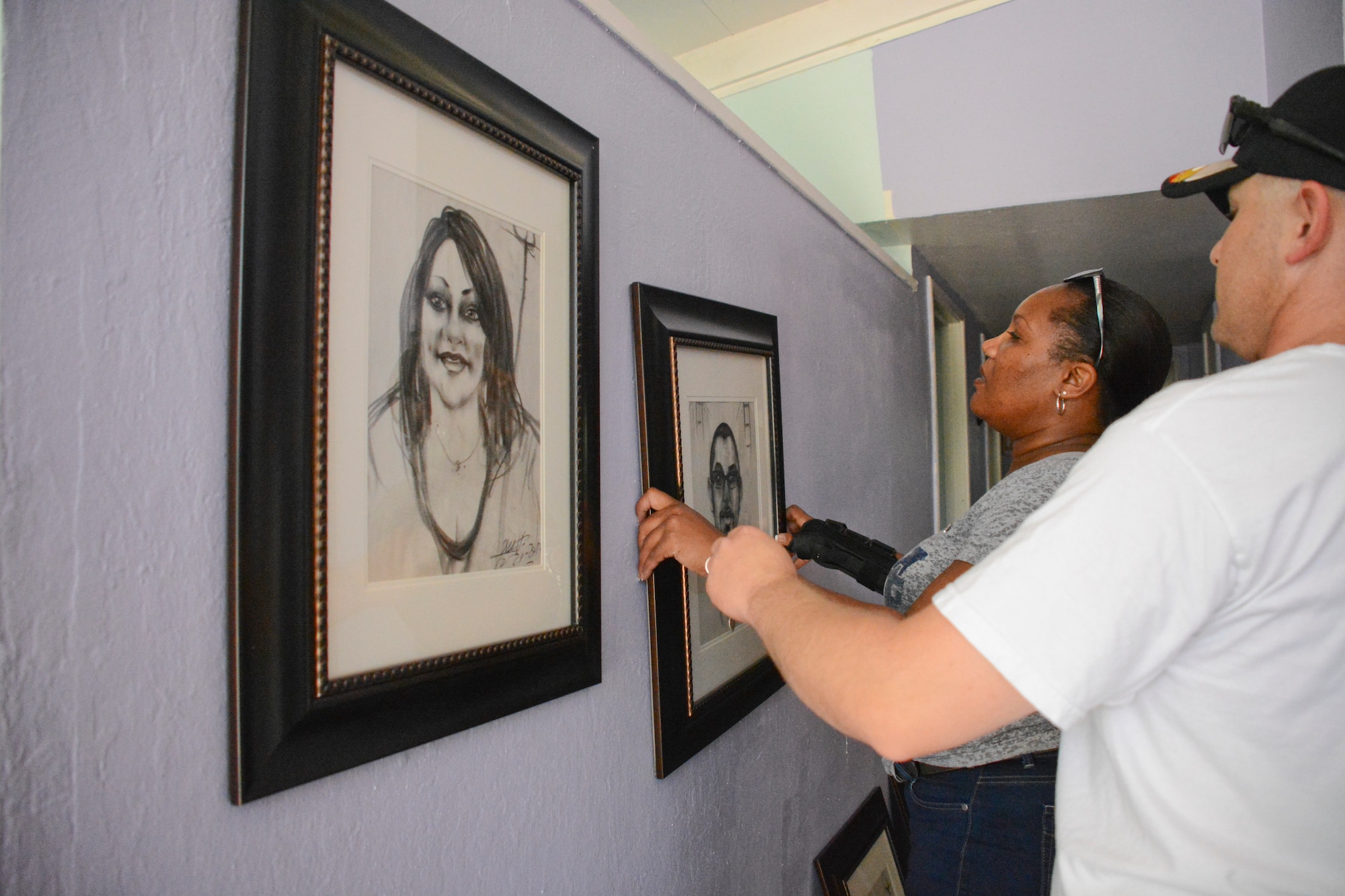 Volunteers hang a picture of the late Airman 1st Class Chris Evans May 9 at the Evans’ residence. The photos were framed and displayed in the center of the home. (U.S. Air Force photo by Airman 1st Class Amber Carter)

