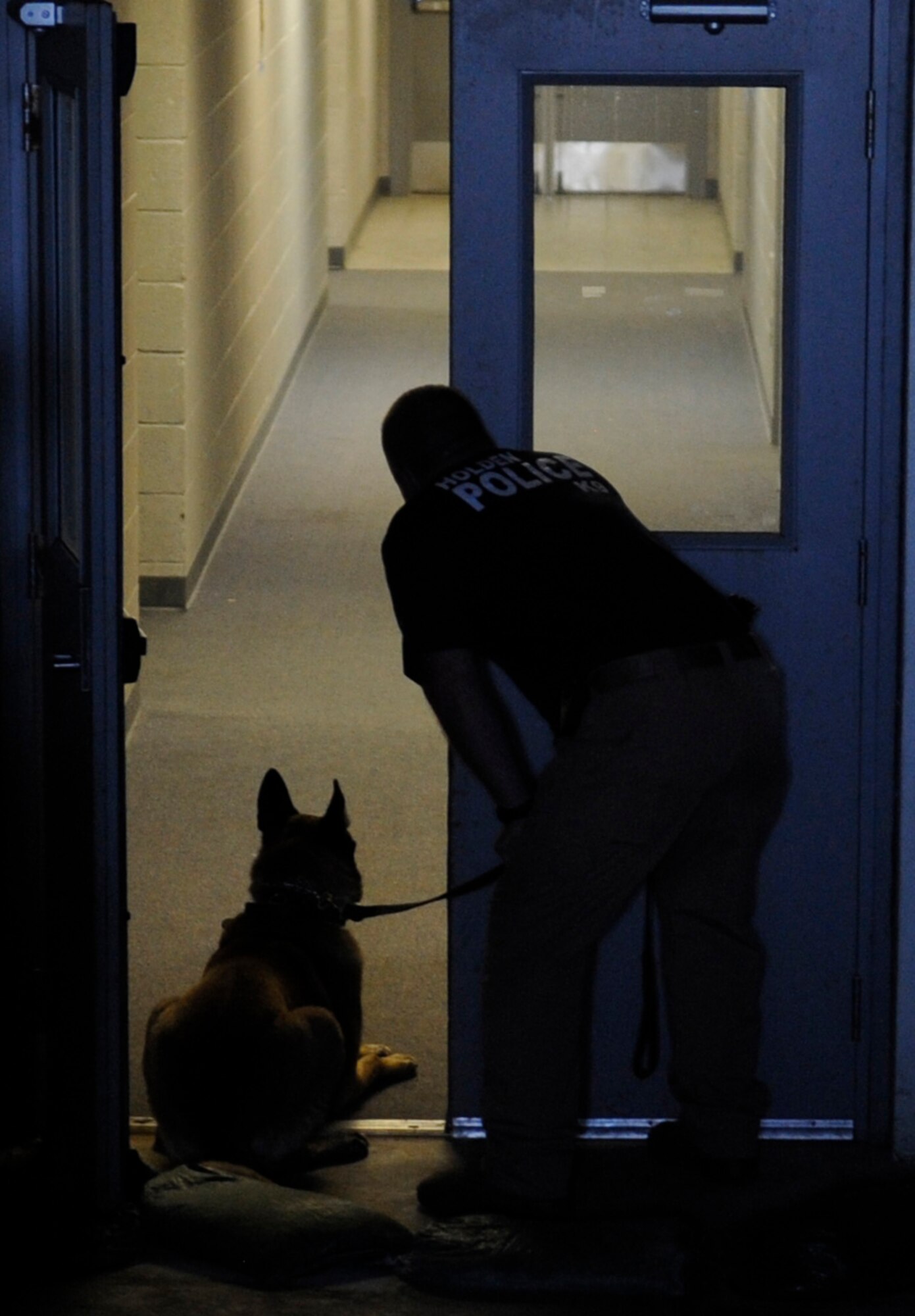 Holden police officer Matt Bond with K-9 Drako, challenges the building before releasing the K-9 off-leash at Whiteman Air Force Base, Mo., April 30, 2015, during a combined training with the 509th Security Forces Squadron military working dog section. The handler challenges the building by calling out to a hidden suspect within the building before releasing the dog to find the suspect.  (U.S. Air Force photo by Staff Sgt. Alexandra M. Longfellow/Released)