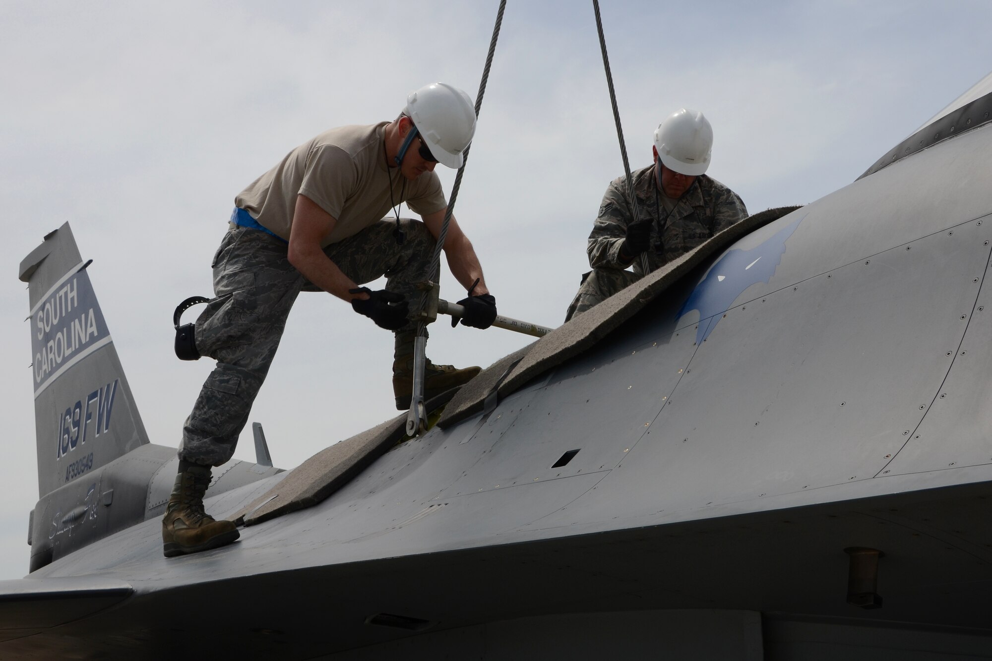 U.S. Air Force Tech. Sgt. Donald Murphy (left), and Airman 1st Class Clifford Derienzo (right), who are both crew chiefs with the 169th Maintenance Squadron attach a spreader bar to an aircraft hoisting sling during a Major Aircraft Recovery Exercise (MARE) May 6, 2015 at McEntire Joint National Guard Base, S.C. The MARE exercise was a base-wide training simulation to determine how McEntire would respond to an aircraft crash. (U.S. National Guard photo by Amn Megan Floyd/Released)