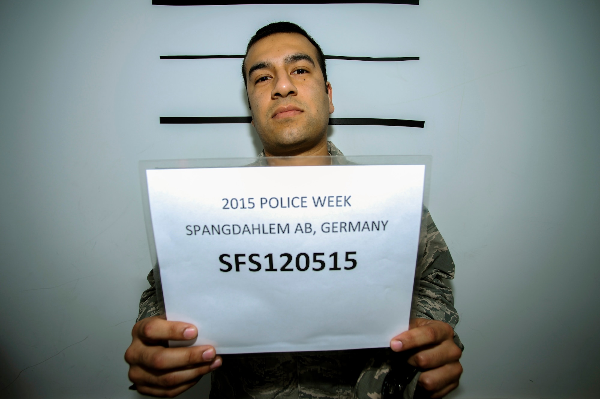 U.S. Air Force Staff Sgt. Jose Punzo, a 52nd Communications Squadron official mail center NCO in charge, poses for a mug shot during the National Police Week Jail and Bail event at the Exchange on Spangdahlem Air Base, Germany, May 12, 2015. A portion of the collected funds will go toward a memorial fund dedicated to fallen police officers. (U.S. Air Force photo by Airman 1st Class Timothy Kim/Released)