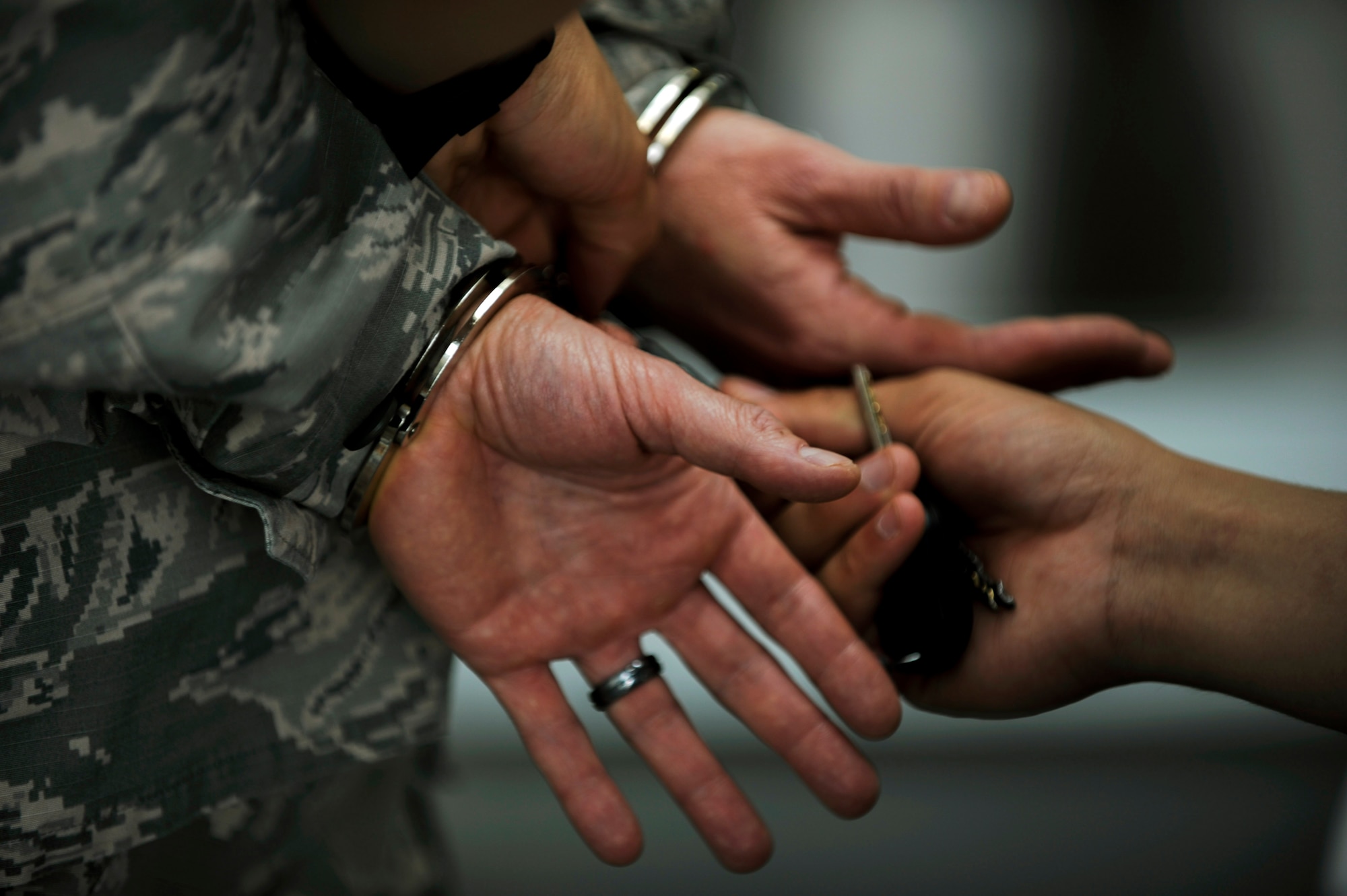 A security forces member removes handcuffs from a suspect during the National Police Week Jail and Bail event at the Exchange on Spangdahlem Air Base, Germany, May 12, 2015. Spangdahlem community members could pay a minimum of $5 to detain a suspect for one hour or $100 for a detention until 4 p.m. (U.S. Air Force photo by Airman 1st Class Timothy Kim/Released)