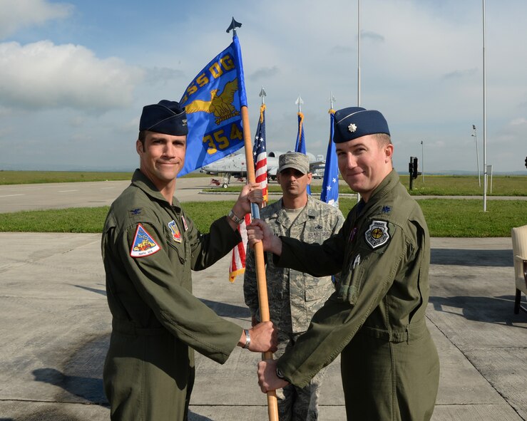 U.S. Air Force Col. Clinton Eichelberger, 355th Operations Group commander, passes the 354th Expeditionary Fighter Squadron guidon to U.S. Air Force Lt. Col. Ryan Hayde during a change-of-command ceremony May 15, 2015, on the flightline at Campia Turzii, Romania. Hayde now leads 12 A-10 Thunderbolt II attack aircraft and more than 300 assigned personnel. (U.S. Air Force photo by Senior Airman Dylan Nuckolls/Released)
