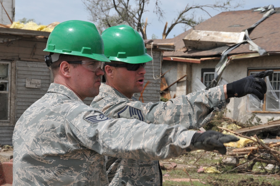 DELMONT, S.D. - Master Sgt. Jacob Erpenbach, 114th Civil Engineer Squadron engineer assistant, directs Tech. Sgt. Zach Jorgenson, 114th Civil Engineer Squadron HVAC superintendent, on the location of the next area to be cleared during the unit's state activation in support of the community of Delmont, S.D.  The unit was sent to Delmont to assist with the tornado recovery efforts after the city was hit by a tornado May 11, 2015.(National Guard photo by Senior Master Sgt. Nancy Ausland/released)