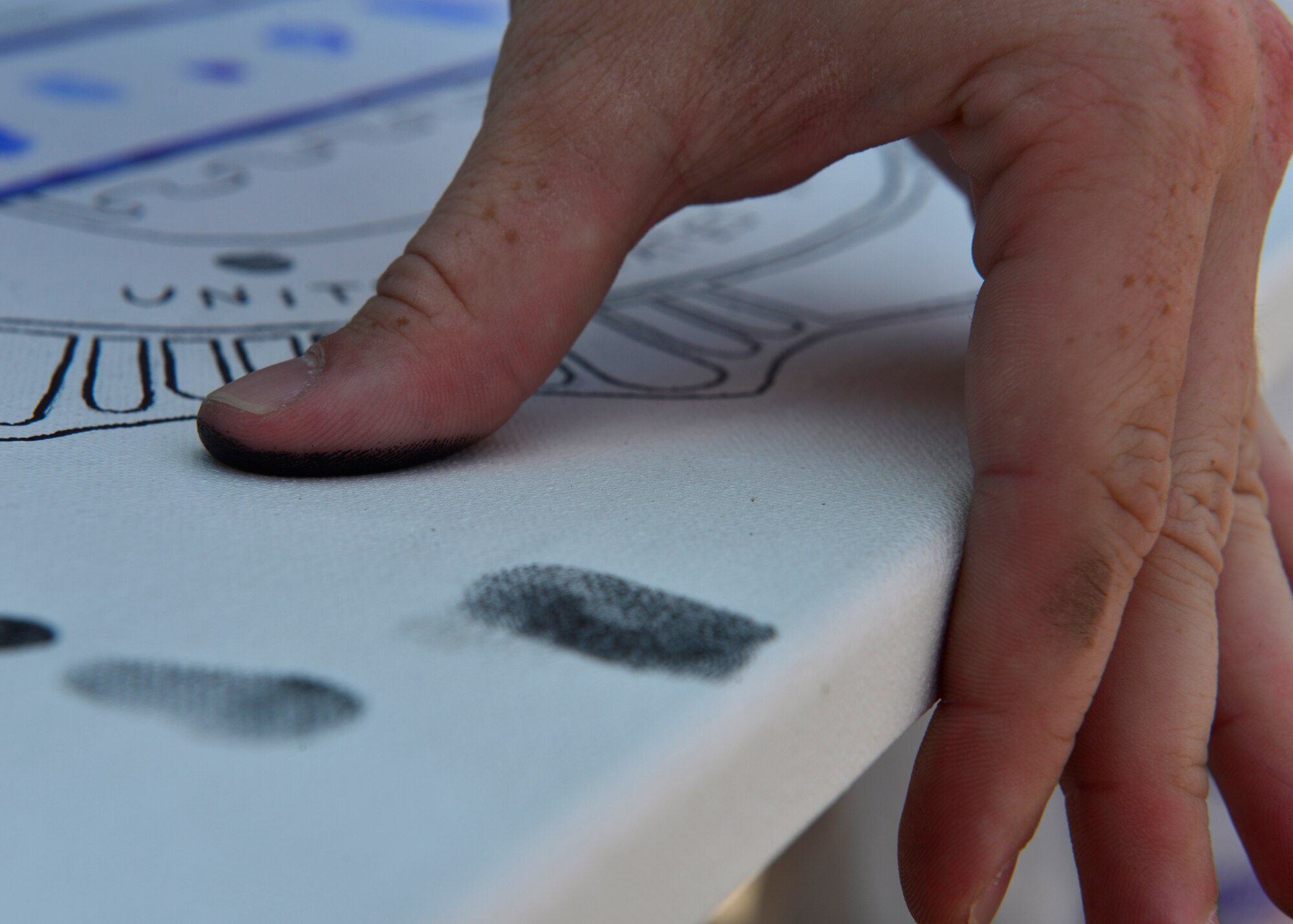A thumb presses against a fingerprint canvass at a police demonstration during Police Week, May 12, 2015, at Aviano Air Base, Italy.  Booths were set up for face and finger painting, thumb printing and combat arms demonstrations.  During the week, ceremonies, memorials and other events took place to honor the men and women who have served in the line of duty. (U.S. Air Force photo by Airman 1st Class Cary Smith/Released)