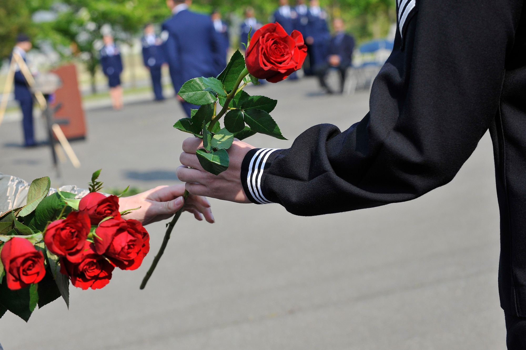 A U.S. Air Force Airman hands a Red Rose to a U.S. Navy sailor during a retreat ceremony at Misawa Air Base, Japan, May 14, 2014. Each red rose signified a fallen Air Force defender and was placed in front of a memorial to commemorate their selfless sacrifice. (U.S. Air Force photo by Senior Airman Jose L. Hernandez-Domitilo/Released)