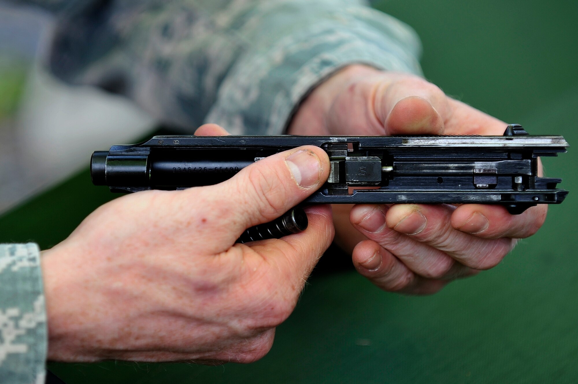 A 35th Security Force Squadron member inspects the slide and barrel of a M9 Berretta as part of a weapons assembly test at Misawa Air Base, Japan, May 14, 2015. As the last phase of a Police Week challenge, Airmen were timed on how fast they could assemble and function check an assortment of weaponry they are qualified to use. (U.S. Air Force photo by Senior Airman Jose L. Hernandez-Domitilo/Released)