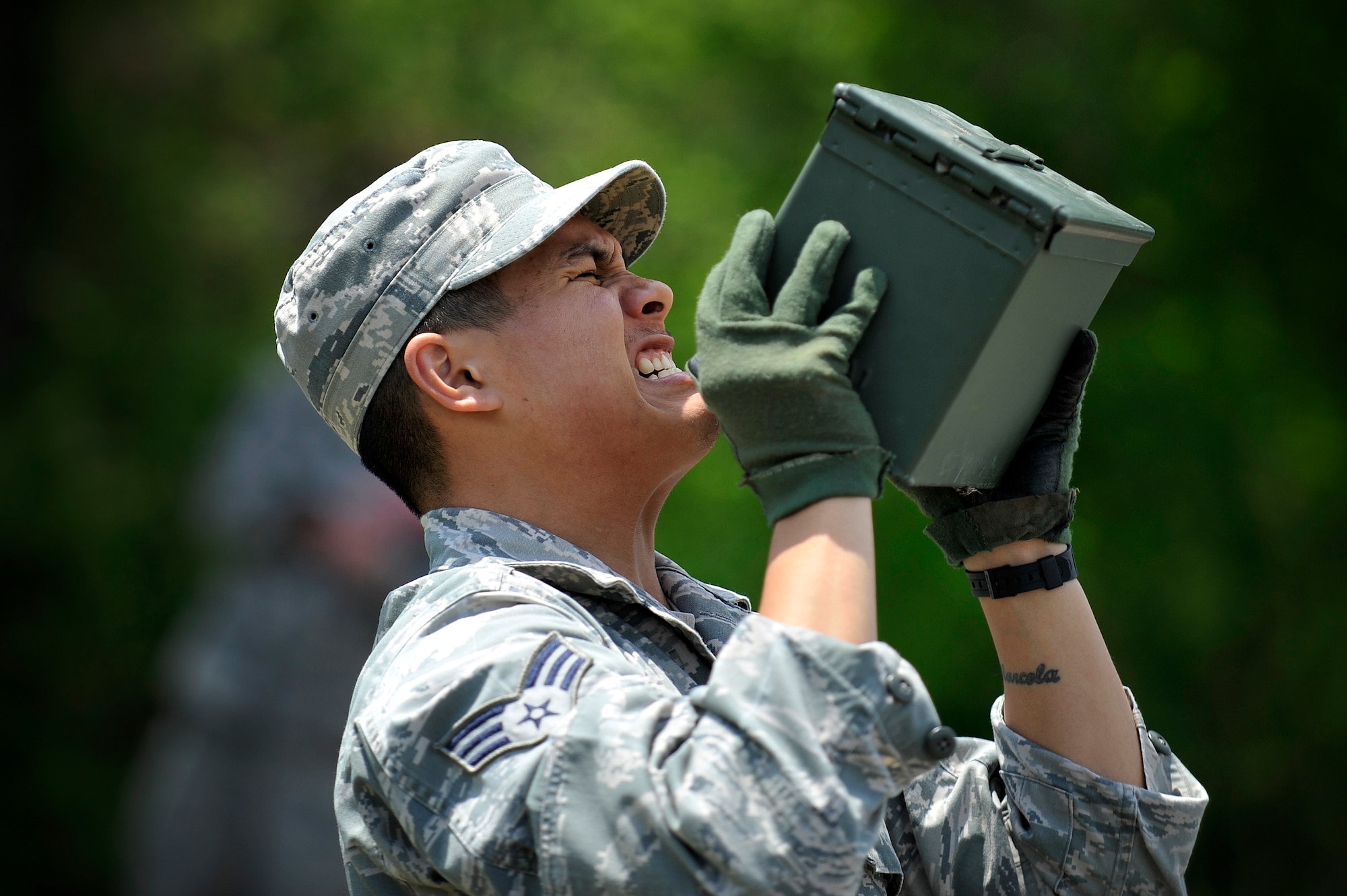 U.S. Air Force Senior Airman Nestor Albalos, 35th Security Squadron Forces installation entry controller, lifts a 30-pound ammunition box over his head at Misawa Air Base, Japan, May 14, 2015. This was part of a Police Week challenge which recorded the maximum number of repetitions an individual could lift an ammunition box over their head. Individual points counted toward an overall team score. (U.S. Air Force photo by Senior Airman Jose L. Hernandez-Domitilo/Released)