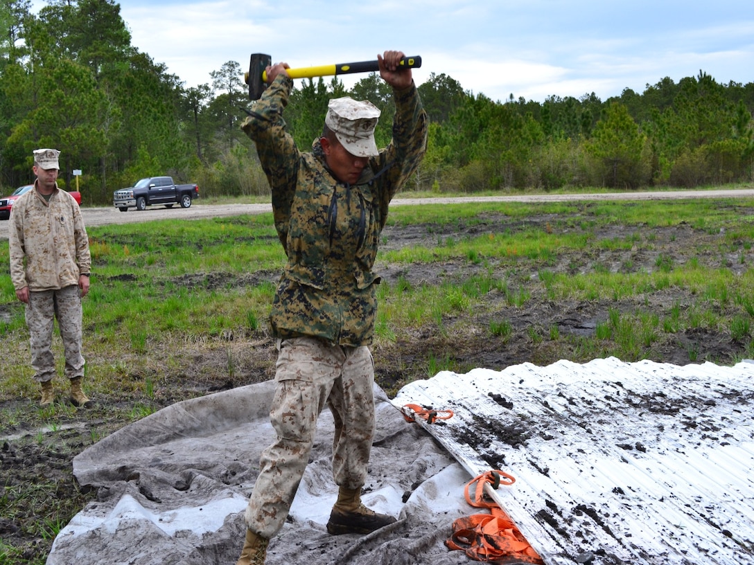 PFC Rai drives an anchor into the ground to secure the matting.