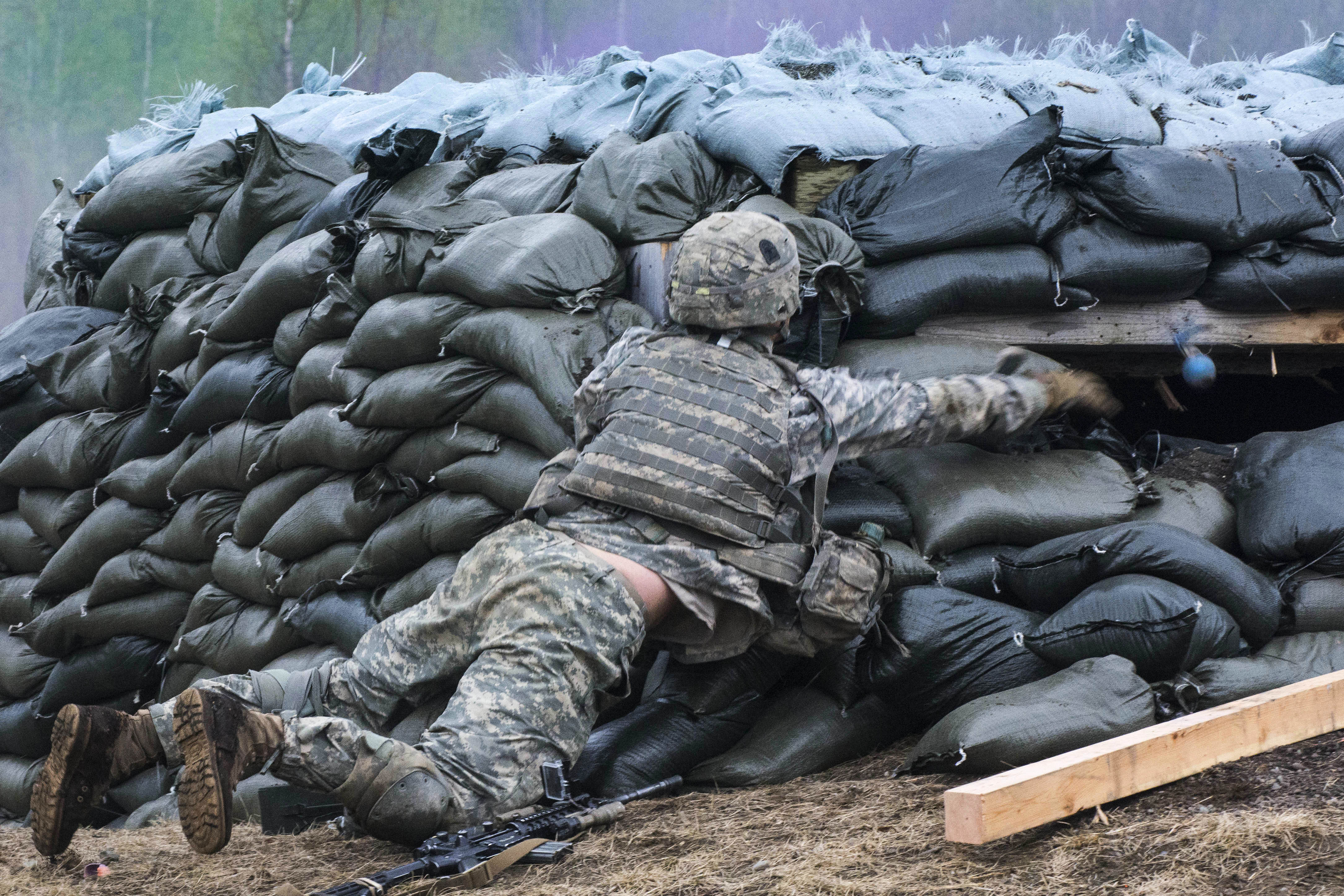 A soldier clears a bunker with a simulated grenade during combined arms