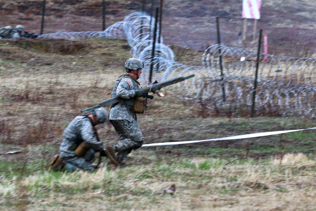 A soldier rushes forward to deliver a bangalore torpedo breaching