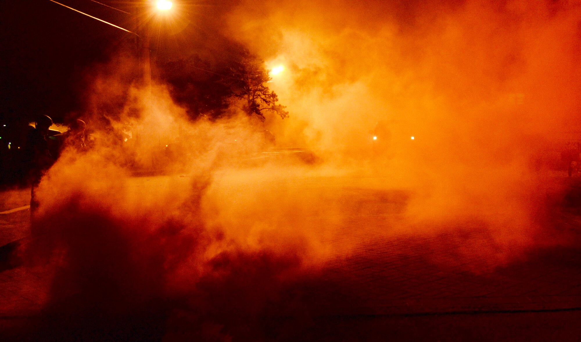 Red smoke from an M18 Smoke Grenade clouds the air in front of the fitness center May 12, 2015, at Osan Air Base, Republic of Korea. The smoke signified the start of a mass causality exercise as part of the readiness exercise Beverly Midnight 15-02. The exercise helps identify areas where procedures should be changed or equipment added in order to enhance the emergency response capabilities. (U.S. Air Force photo by Staff Sgt. Benjamin Sutton/Released) 