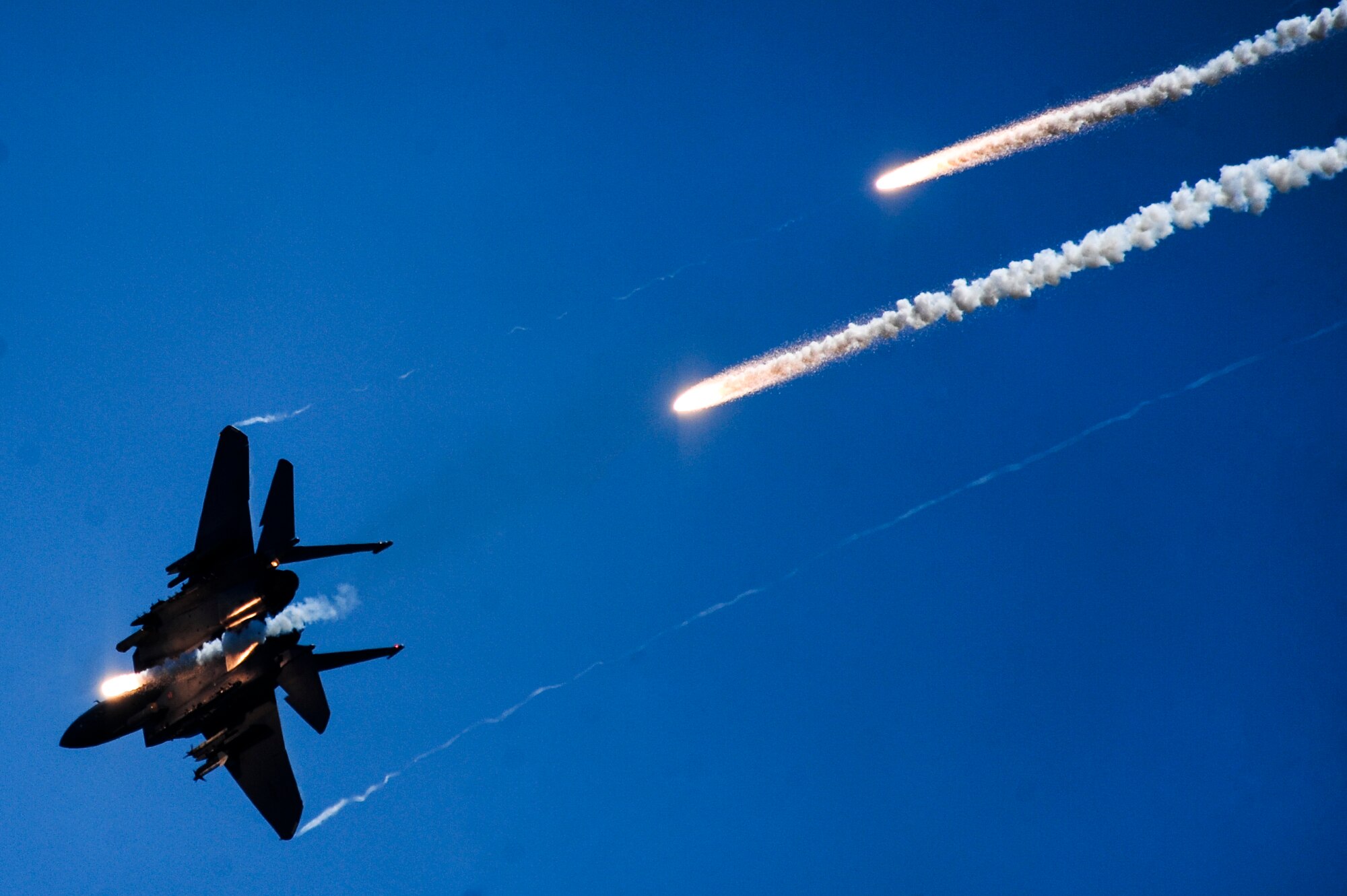 An F-15E Strike Eagle fires multiple flares during a Combined Arms Demonstration as part of the 2015 Wings Over Wayne Air Show, May 17, 2015, at Seymour Johnson Air Force Base, North Carolina. An aerial team of four Strike Eagles and two A-10 Warthogs joined forces to simulate taking over an airfield by eliminating enemy ground forces. (U.S. Air Force photo/Senior Airman Brittain Crolley)