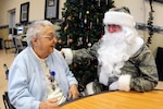 Chief Master Sgt. Paul Tangen, of the 119th Wing, dons a specially made camouflage Santa suit as he greets residents Dec. 15 during the annual North Dakota National Guard Christmas party at the North Dakota Veterans Home in Lisbon, N.D. North Dakota Air and Army National Guardmembers make personal donations to raise money for gifts and present them to the veterans at the nursing home each year during the holiday season. 