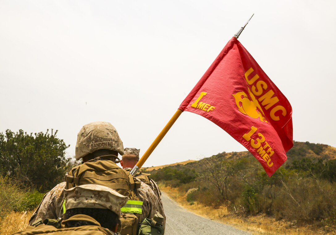 Sgt. Erik Sandoval, a motor transport operator with the 13th Marine Expeditionary Unit, carries the 13th MEU guidon aboard Camp Pendleton, Calif., during a sustainment hike to the machine gun range as part of Command Post Exercise 1, May 14, 2015. The exercise served to test the unit's command and control ability as well as satisfy annual training requirements.