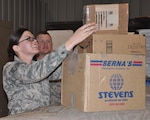Staff Sgt. Robert W. Monohan, American Forces Network Theater Maintenance Technician, looks on as Staff Sgt. Jessica L. King, AFN Bagram News NCOIC, picks up holiday packages for her unit at the Bagram Airfield post office.