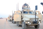 A line of Mine Resistant Ambush Protected vehicles operated by Soldiers with Company F, 3rd Battalion, 116th Cavalry Regiment, 3rd Sustainment Brigade, 103rd Sustainment Command (Expeditionary), stand ready to begin a convoy recently at Joint Base Balad, Iraq.