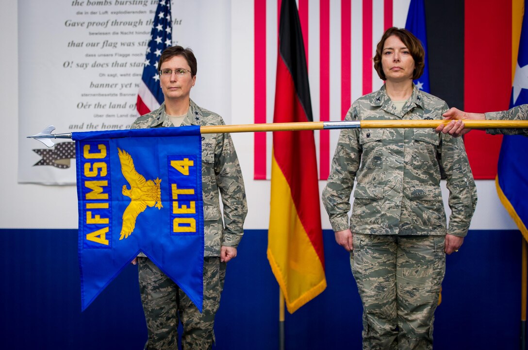 Maj. Gen. Theresa Carter, Air Force Installation and Mission Support Center commander, and Col. Andra Clapsaddle, AFIMSC Detachment 4 commander, stand at attention as the detachment 4 guidon is unfurled during an assumption of command ceremony May 15, 2015, at Ramstein Air Base, Germany. AFIMSC is establishing detachments at each major command in order to best support the needs the management and operation of its installations while leveraging centralized capabilities in the AFIMSC headquarters, its six primary subordinate units and two direct reporting units. (U.S. Air Force photo/Tech. Sgt. Ryan Crane)