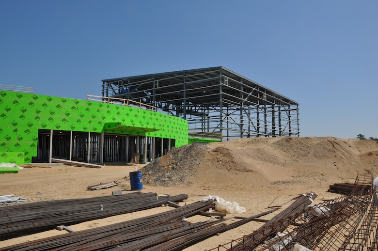 A view of the front of the complex looking northeast.  The curved shape with green board is the administration area and the steel frame beyond is the high-bay hanger. 