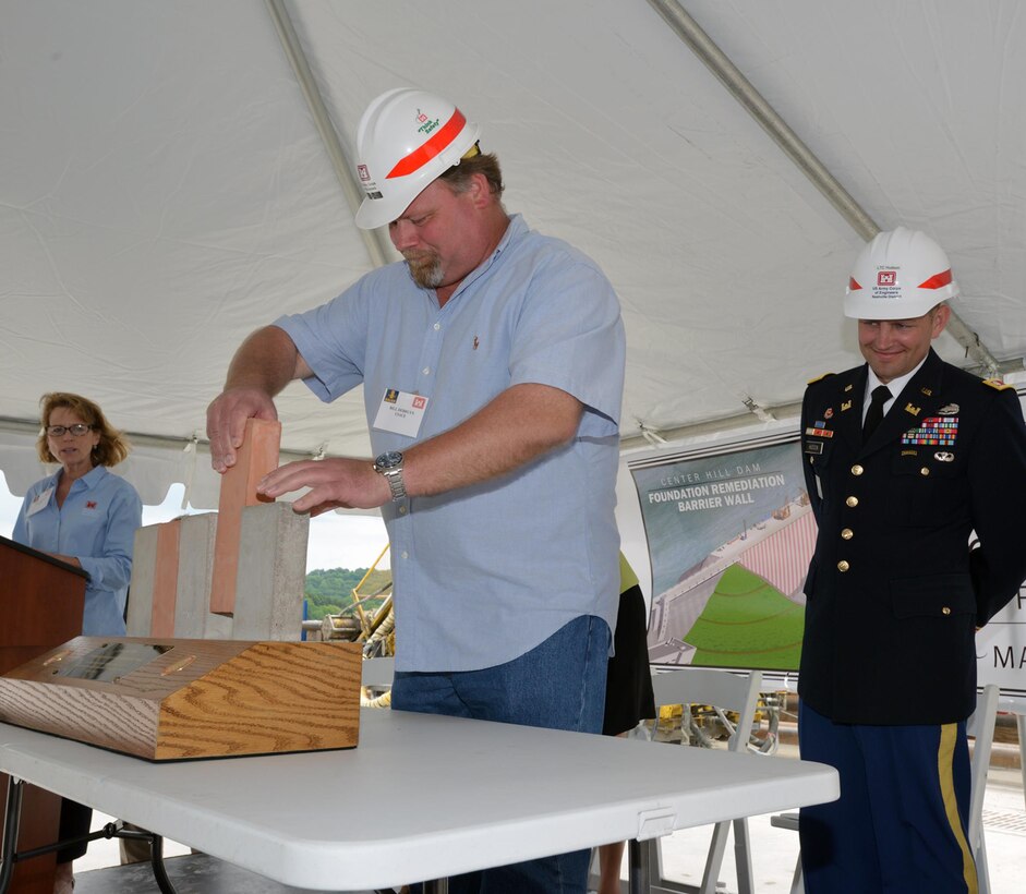 Bill DeBruyn, resident engineer for the  Center Hill Dam Foundation Remediation Project,place a ceremonial concrete form into a small-scale model commemorating the completion of the Center Hill Dam Barrier Wall Project May 18, 2015 on the work platform of the dam.  