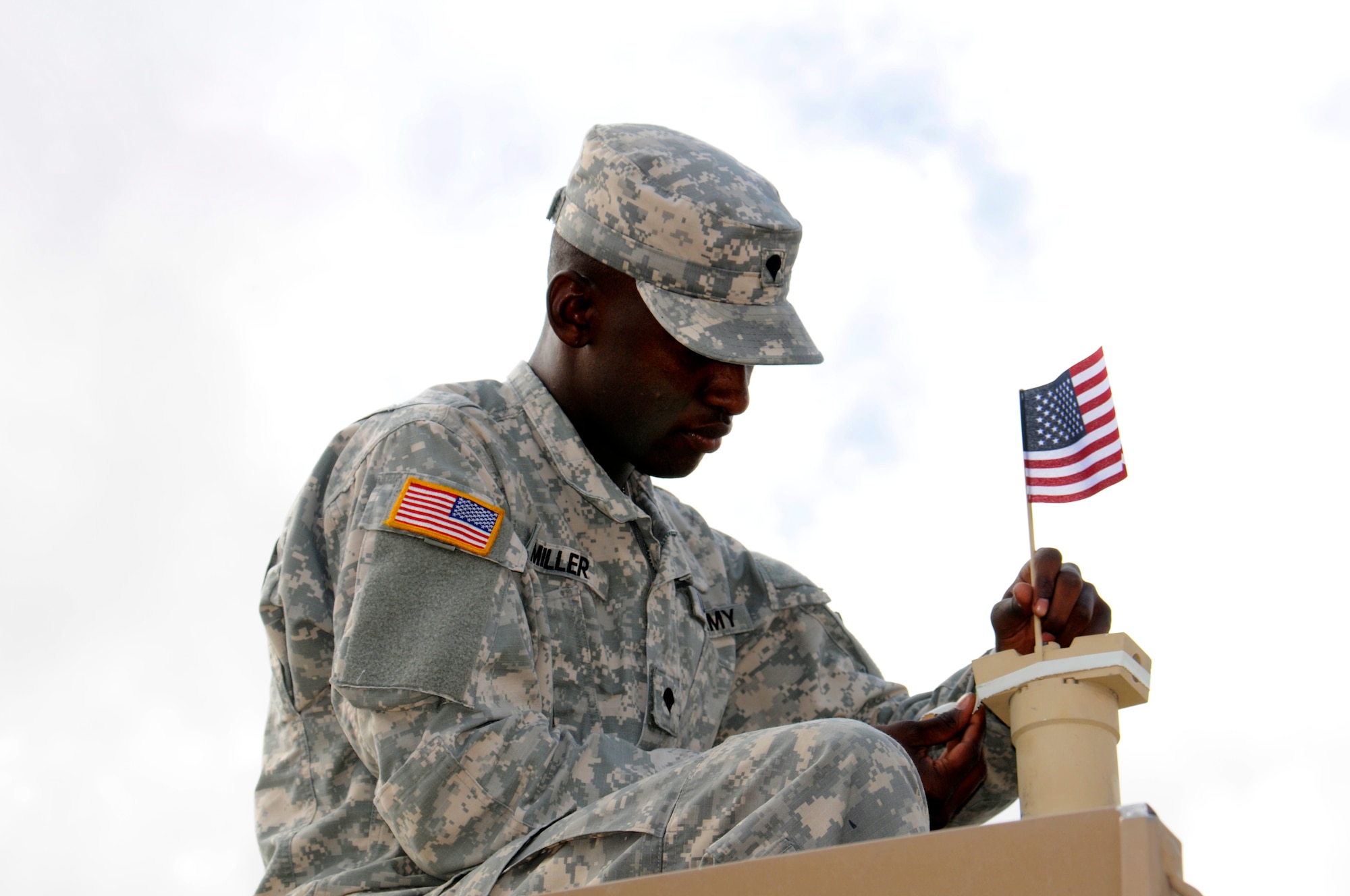 A soldier from Fort Irwin attaches a flag to a military vehicle prior to the annual Torrance Armed Forces Day parade, May 16.  (Photo by Joe Juarez) 