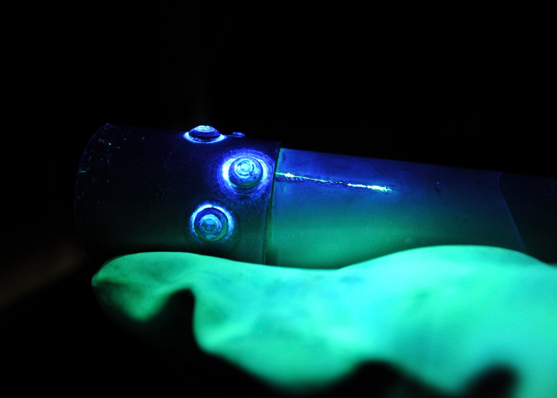 Airman 1st Class Royston Bedminster, 28th Maintenance Squadron nondestructive inspection technician, inspects part of an actuator under black lights at Ellsworth Air Force Base, S.D., May 8, 2015. Under black light, imperfections appear as green lines allowing NDI to determine the length and location of cracks, helping to prevent any major damages to aircraft. (U.S. Air Force photo by Senior Airman Anania Tekurio/Released) 