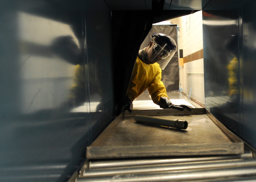Airman 1st Class Royston Bedminster, 28th Maintenance Squadron nondestructive inspection technician, sends part of an actuator through a developer machine during an inspection at Ellsworth Air Force Base, S.D., May 8, 2015. During the developer stage, water suspended powder is applied, pulling penetrant from the cracks to enhance visual inspection when finally examined under black lights. (U.S. Air Force photo by Senior Airman Anania Tekurio/Released)