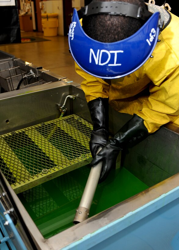 Airman 1st Class Royston Bedminster, 28th Maintenance Squadron nondestructive inspection technician, dips part of an actuator into penetrant liquid at Ellsworth Air Force Base, S.D., May 8, 2015. Penetrant testing is a cost effective method of detecting surface cracks, corrosion, scratches and other surface impurities that could hinder mission readiness of the B-1. (U.S. Air Force photo by Senior Airman Anania Tekurio/Released)