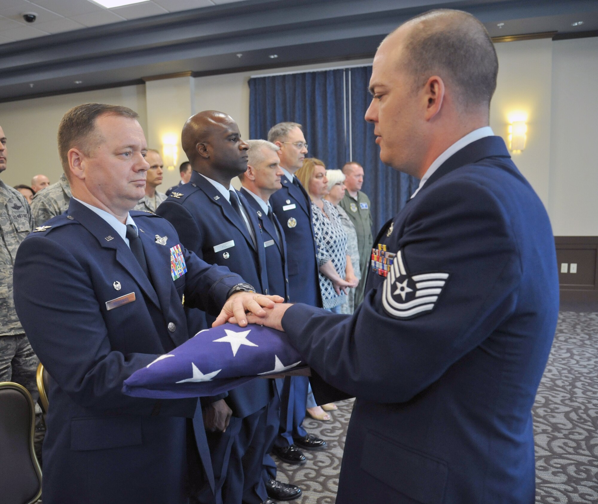 Tech. Sgt. Aaron Ramos, 92nd Aircraft Maintenance Squadron electrical environmental craftsman, presents the American flag to Col. Brian McDaniel, 92nd Air Refueling Wing commander, during the Honor Guard graduation May 15, 2015, in the Red Morgan Center at Fairchild Air Force Base, Wash. A six-man team folds the flag in honor of the deceased during an active duty funeral and then presents the flag to next-of-kin. (U.S. Air Force photo/Staff Sgt. Samantha Krolikowski)