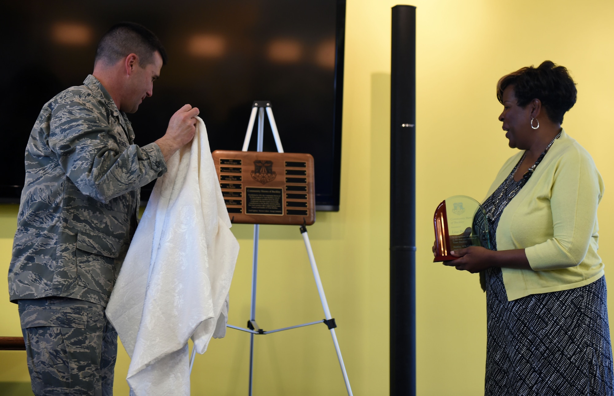 Col. John Wagner, 460th Space Wing commander, left; presents Lisa R. Buckley, American Automation Building Solutions Inc. chief of operations, right; the Community Heroes of Buckley plaque with her name on it May 14, 2015, at the Panther Den on Buckley Air Force Base, Colo. Every year, Buckley Air Force Base recognizes one individual from the local community for their efforts made toward supporting Team Buckley by presenting them the Community Hero of Buckley award. (U.S. Air Force Photo by Airman 1st Class Emily E. Amyotte/Released)