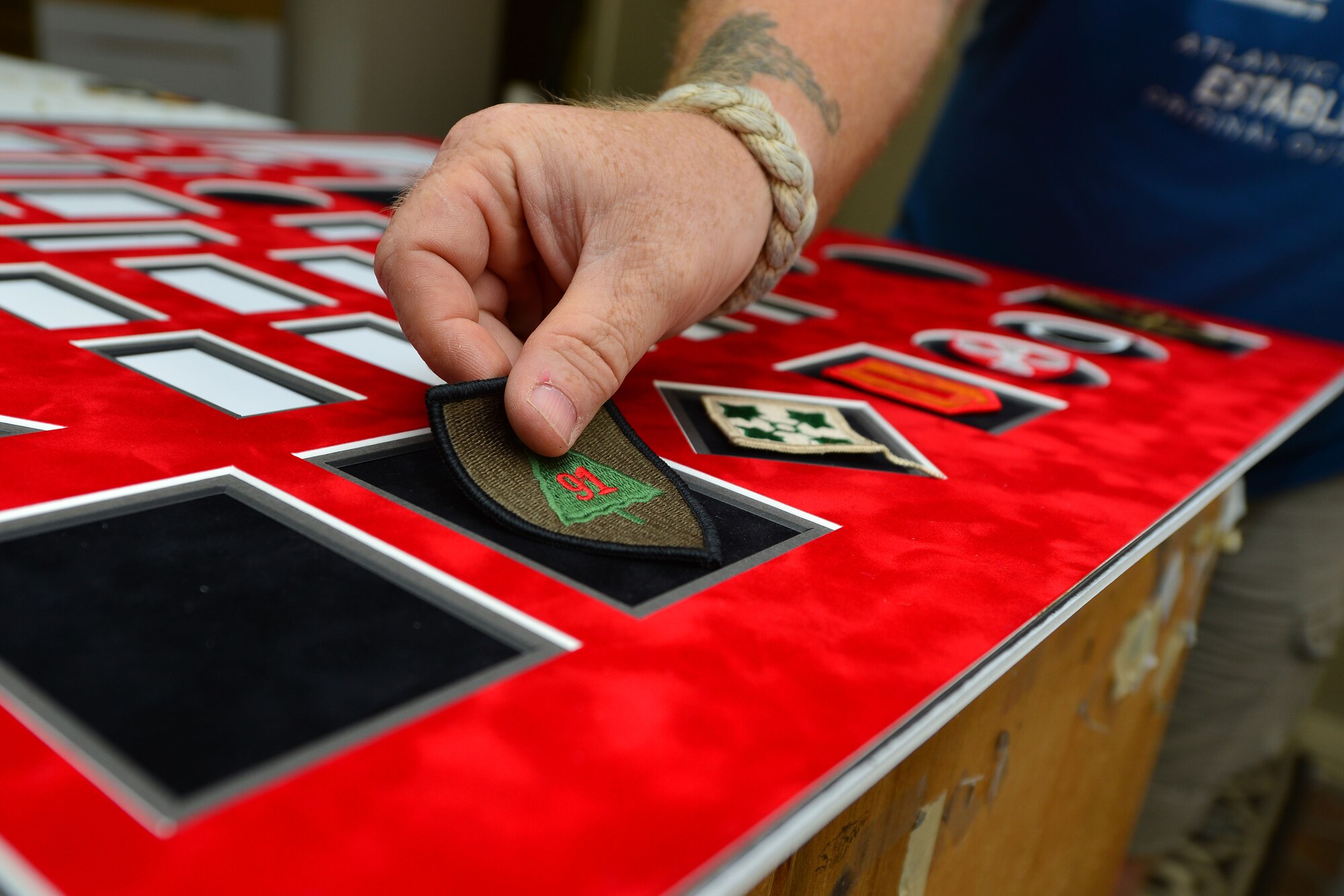 Mark Winslow, 733rd Mission Support Division Morale, Welfare and Recreation frame shop technician, places a patch on matting for a shadow box at Fort Eustis, Va., May 12, 2015. Shadow boxes can contain a variety of memorabilia collected throughout U.S. Service members’ careers. This box included patches, coins, medals, duty badges and a name plate. (U.S. Air Force photo by Staff Sgt. Natasha Stannard/Released)