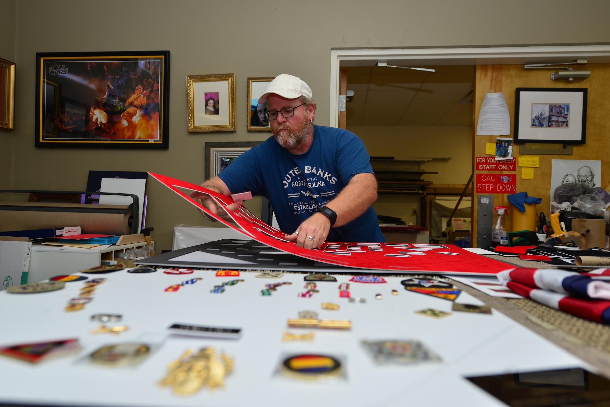 Mark Winslow, 733rd Mission Support Division Morale, Welfare and Recreation frame shop technician, lays out matting material for a retirement shadow box at Fort Eustis, Va., May 12, 2015. Winslow creates shadow boxes and other framing devices for ceremonial pieces, art work, photography and more. (U.S. Air Force photo by Staff Sgt. Natasha Stannard/Released)