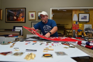Mark Winslow, 733rd Mission Support Division Morale, Welfare and Recreation frame shop technician, lays out matting material for a retirement shadow box at Fort Eustis, Va., May 12, 2015. Winslow creates shadow boxes and other framing devices for ceremonial pieces, art work, photography and more. (U.S. Air Force photo by Staff Sgt. Natasha Stannard/Released)