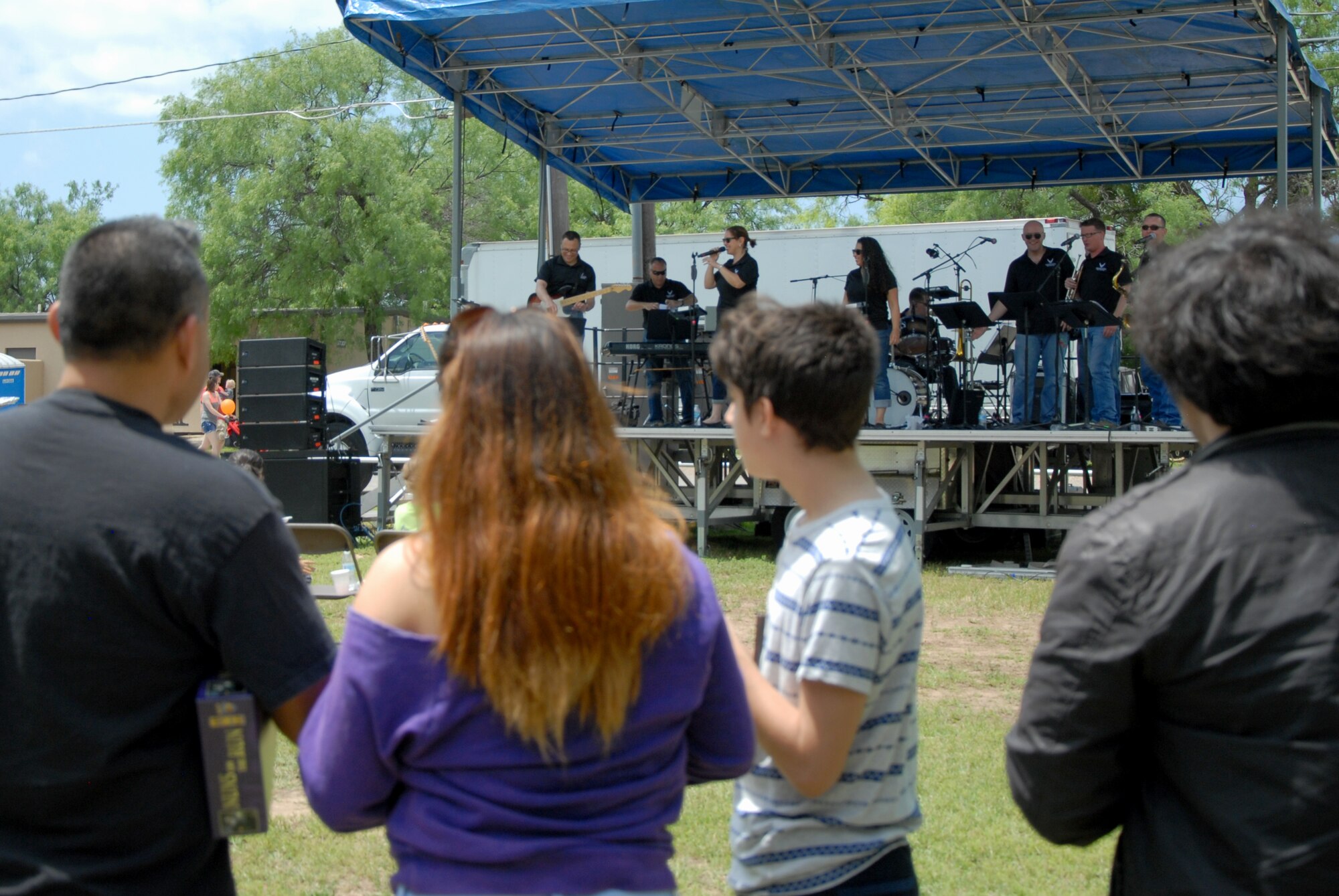A family watches Air Force Band of the West “Warhawk” perform during Goodfellow Appreciation Day at the Goodfellow Recreation Camp in San Angelo, Texas, May 16, 2015. Warhawk traveled from Joint Base San Antonio, Texas, to perform at the event. (U.S. Air Force photo by Senior Airman Joshua Edwards/ Released)