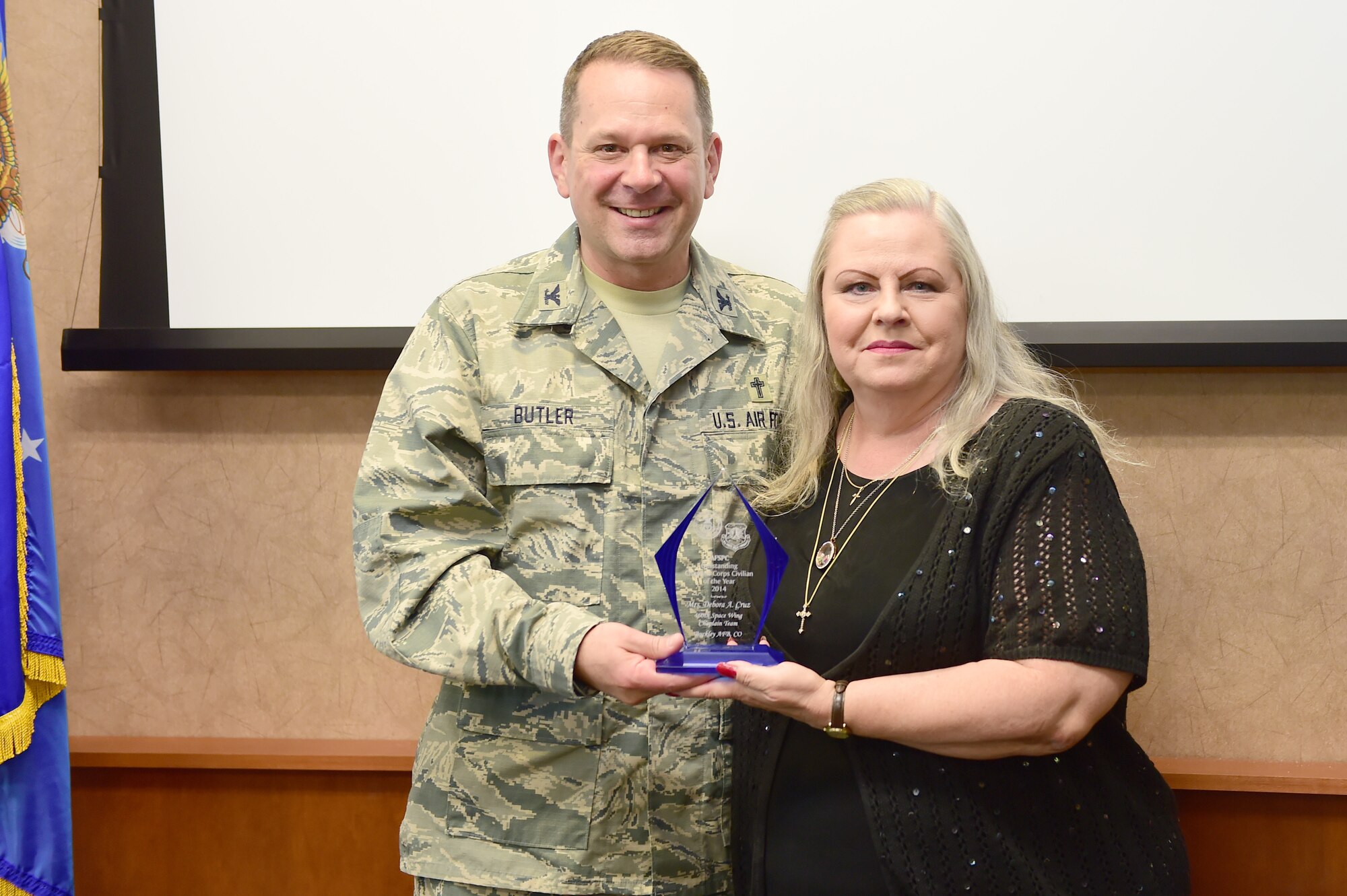 Col. Timothy A. Butler, Air Force Space Command command chaplain, left; awards Debbie Cruz, 460th Space Wing chapel secretary, right; AFSPC Chaplain Core Civilian of the Year May 18, 2015, on Buckley Air Force Base, Colo. The chaplain core civilian of the year award encompasses all civilians that work within the chaplain core. With her victory at the AFSPC level, Cruz will now go on to compete at the Air Force level. (U.S. photo by Airman 1st Class Luke W. Nowakowski/Released) 