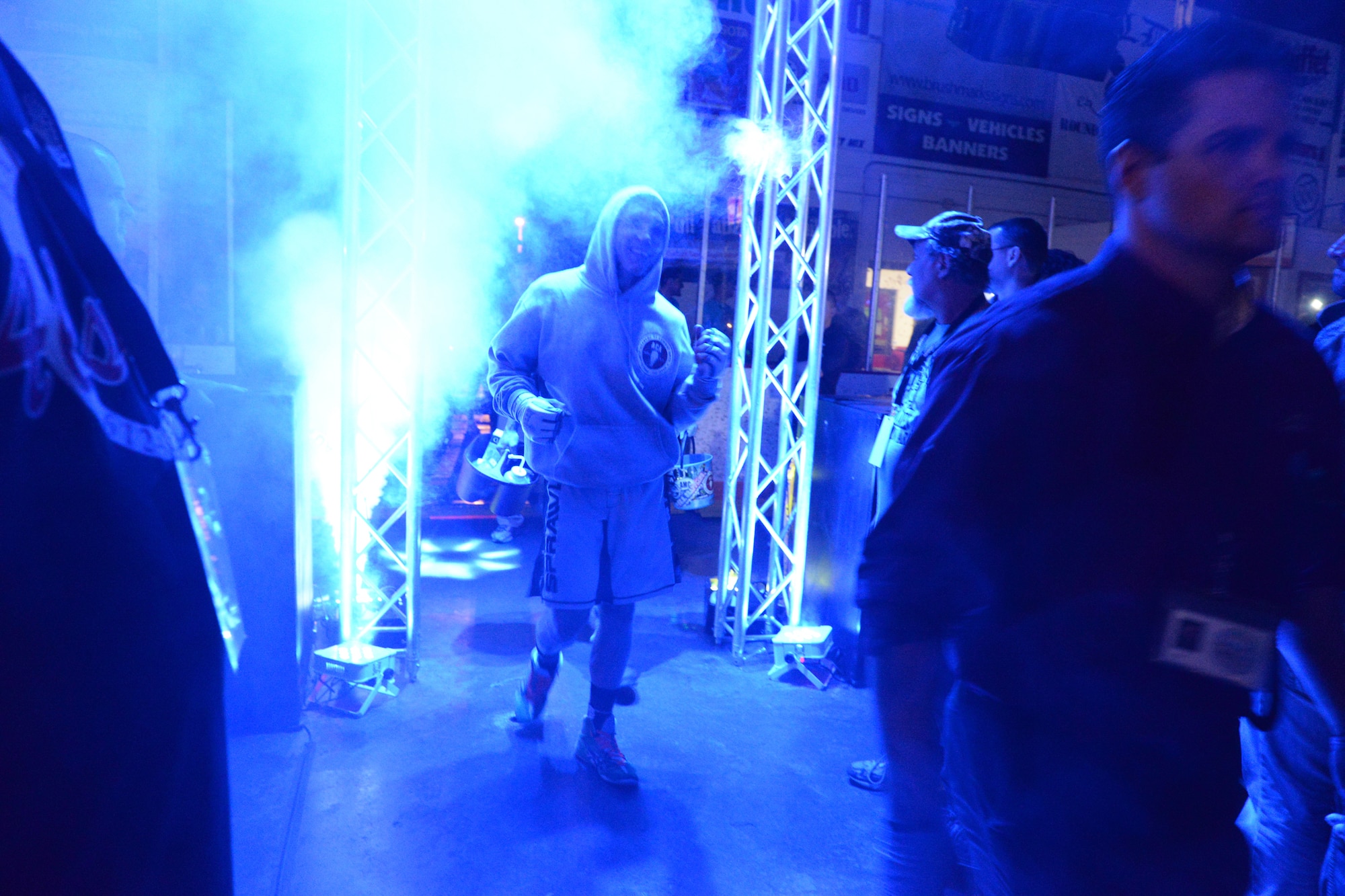 Senior Airman Michael Bullen, of the 119th Security Forces Squadron, makes a s smoky entrance through the dimly lit crowd leading to the center stage fighting cage where he will compete in a mixed martial arts fight at the Freeman Arena, Detroit Lakes, Minnesota, May 16, 2015.  The security forces Airman uses mixed martial arts training and fighting to enhance his fitness and skills to be better prepared in his career field and to be better prepared for potential threats on duty.  (U.S. Air National Guard photo by Senior Master Sgt. David H. Lipp/Released)
