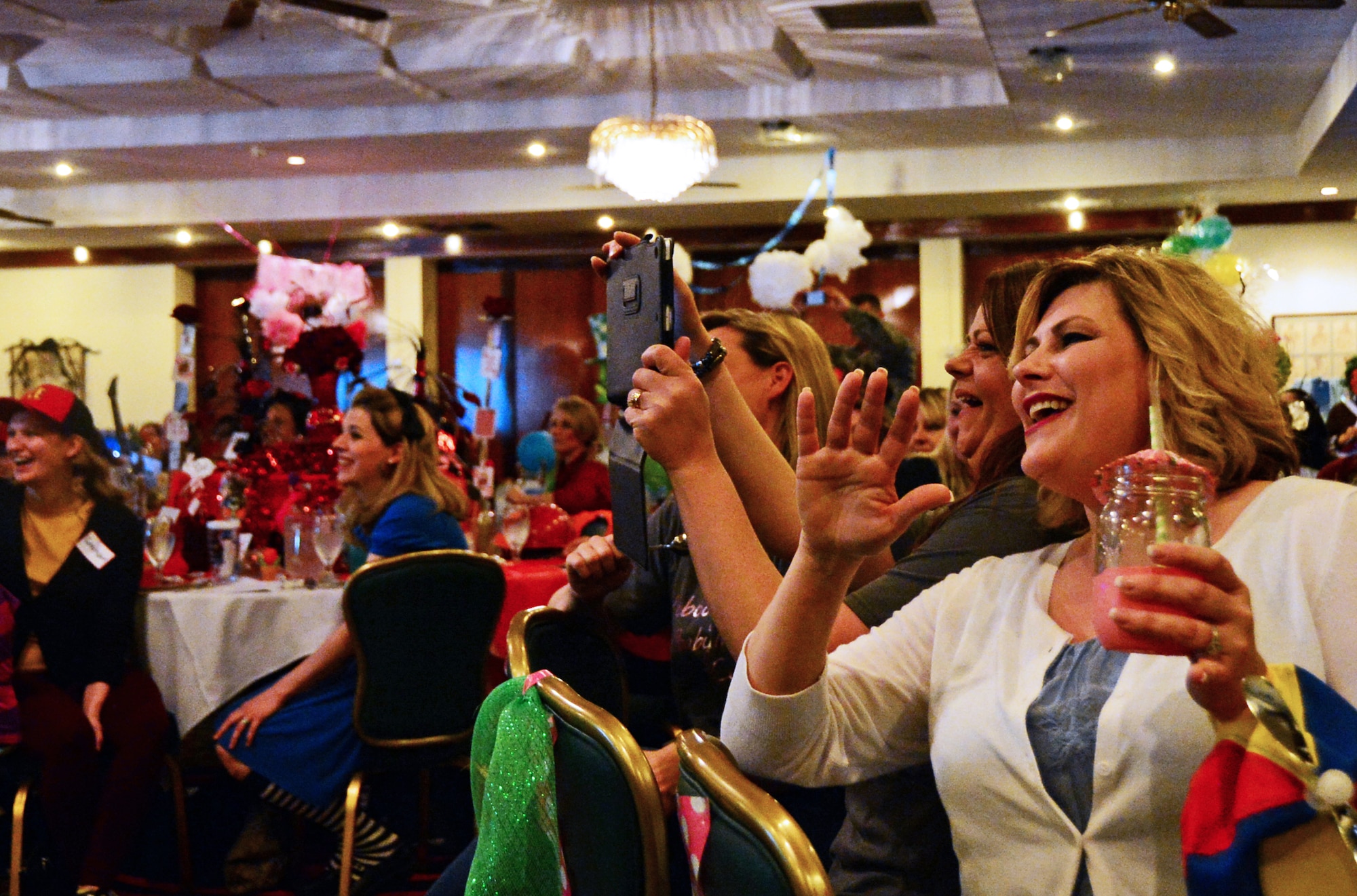 Spouses from the 48th Fighter Wing cheer during the movie-themed Liberty Spouses Dining-In at Royal Air Force Lakenheath, England, May 8, 2015. The event gave spouses the opportunity to interact with other participants, both in their unit and throughout the greater spouse community. (U.S. Air Force photo by Senior Airman Erin O’Shea/Released)