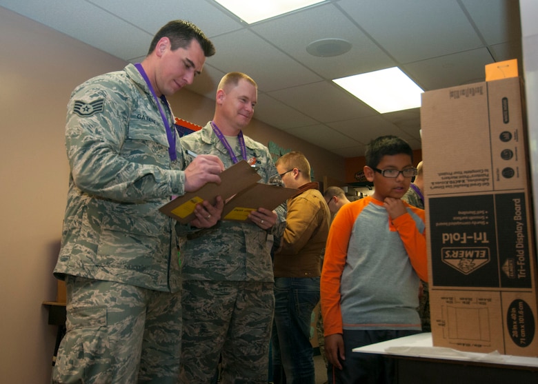 Staff Sgt. Salvatore Catanese, 3rd Space Experimentation Squadron, and Master Sgt. Shawn Stepanek, 7th Space Operations Squadron, grade an Ellicott Elementary school science experiment at the Ellicott science fair May 14, 2015, in Ellicott, Colo. More than a dozen Schriever members volunteered to judge the science fair for the school as part of a community involvement and outreach program. (U.S. Air Force photo| Senior Airman Naomi Griego)