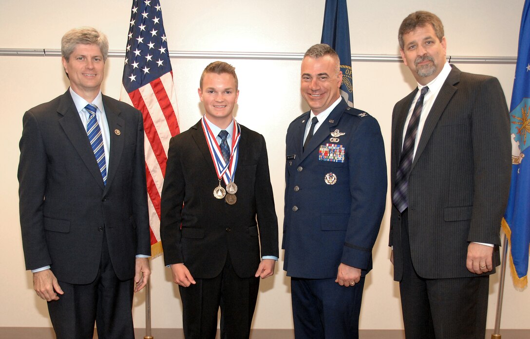 Andrew Eisert, son of retired Air Force Lt. Cols. Gerard and Dawn Eisert, poses for a picture after being awarded a Congressional Gold Medal by Congressman Jeff Fortenberry, left, during a ceremony May 8 at the Bellevue Public Schools Welcome Center in Bellevue, Nebraska.  The Congressional Awards program recognizes youth, ages 14 through 23, who achieve personal goals in public service, personal development, physical fitness and completion of an expedition or exploration. Eisert was one of four Sarpy County students to earn a Congressional Gold Medal while 13 others received silver and bronze medals or certificates. Air Force Col. Mark Williamson, 55th Wing vice commander at Offutt Air Force Base, and Frank Harwood, Bellevue Public Schools superintendent, right, also participated in the ceremony. The annual awards program is administered by the 55th Force Support Squadron and Bellevue Public Schools. (U.S. Air Force photo by Delanie Stafford / Released)