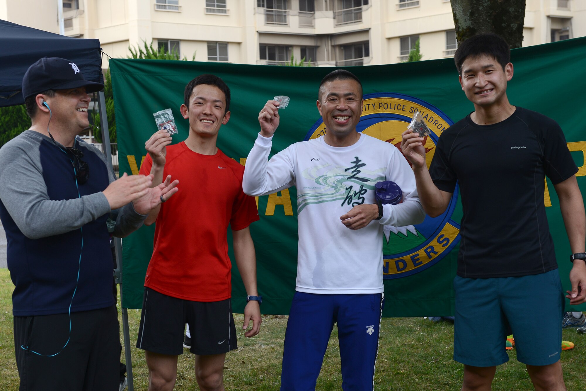 The first three runners display their 374th Security Forces Squadron coins after completing the Police Week 5K at Yokota Air Base, Japan, May 12, 2015.  The coins were presented to them by Maj. Jeffery Day, 374 SFS commander. (U.S. Air Force photo by Airman 1st Class David C. Danford/Released)