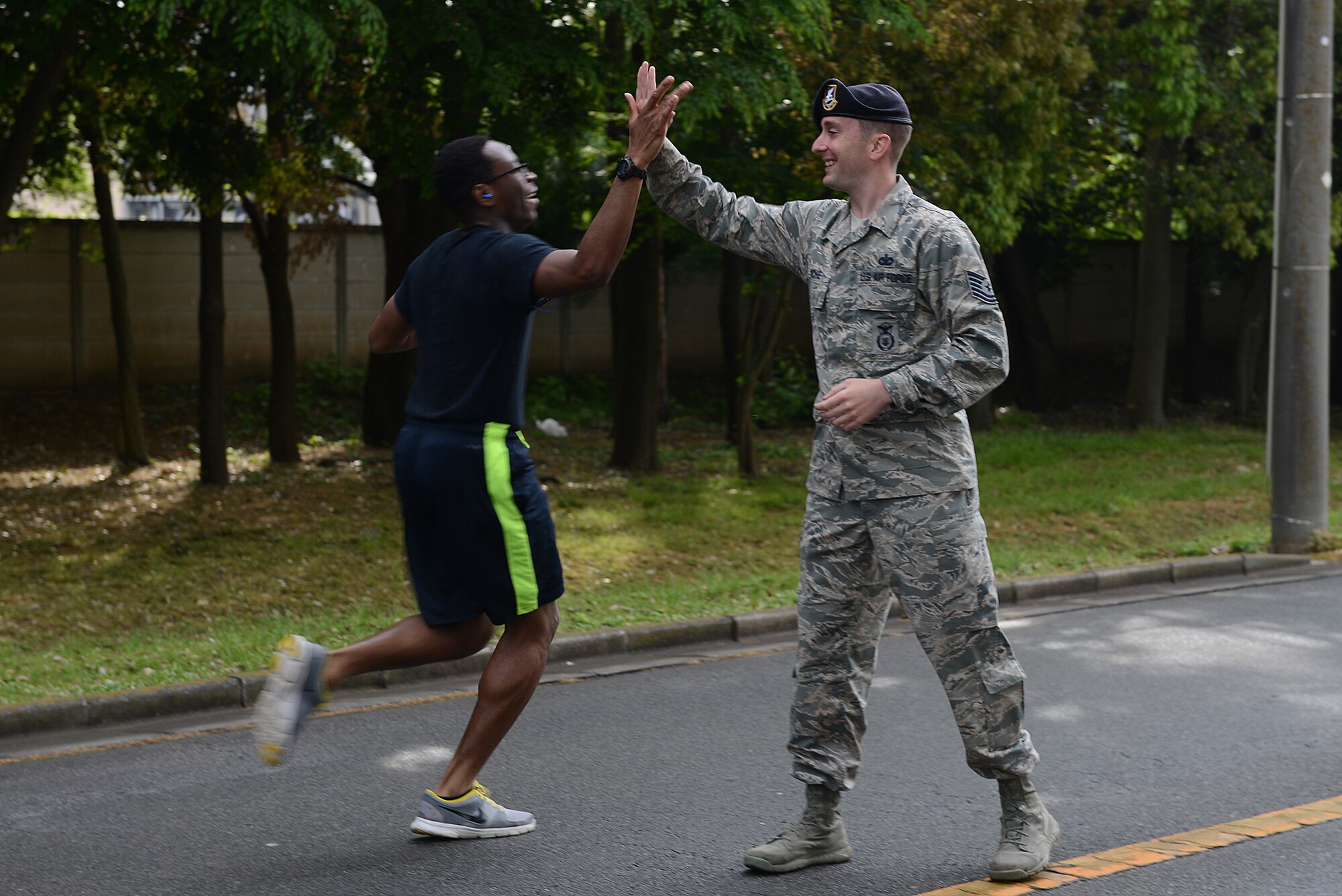 Tech. Sgt. Jonathan Roche, 374th Security Forces Squadron NCO in charge of physical security and resource protection, gives high-fives to runners taking part in the Police Week 5K at Yokota Air Base, Japan, May 12, 2015. President John F. Kennedy signed a proclamation in 1962 designating May 15 as Peace Officers Memorial Day and the week in which that date falls as Police Week. (U.S. Air Force photo by Airman 1st Class David C. Danford/Released)