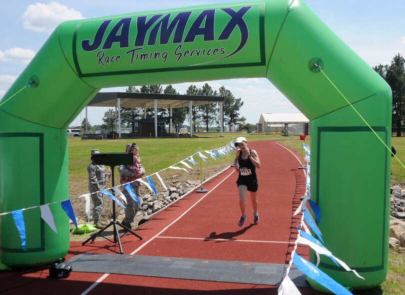 Jennifer Barker crosses the finish line to earn first place among all females during the Hawg Jawg, May 2, 2015, held at Ebbing Air National Guard Base, Fort Smith Ark. Col. Bobbi Doorenbos, 188th Wing commander, presented medals to all the top athletes in their respective age categories. (U.S. Air National Guard photo by Senior Airman Cody Martin/released)