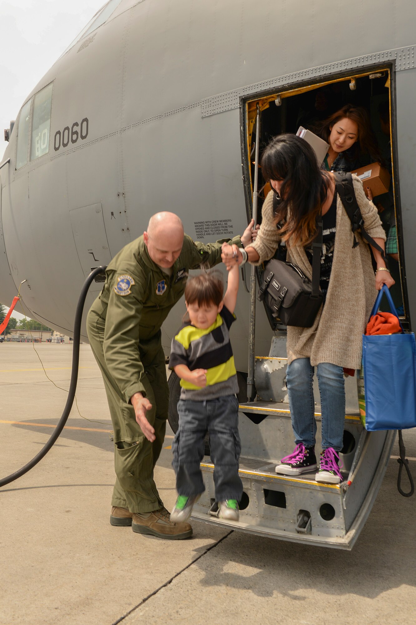 Master Sgt. Brett Brandemuhl, loadmaster with the 144th Airlift Squadron, Alaska Air National Guard, assists dependents of military members assigned to Osan Air Base, Korea, as they step off at Yokota Air Base, Japan, May 15, 2015. The AANG supported Yokota during a test of the “total force” concept, which integrates assets from multiple bases for one mission. (Airman 1st Class Elizabeth Baker/Released)