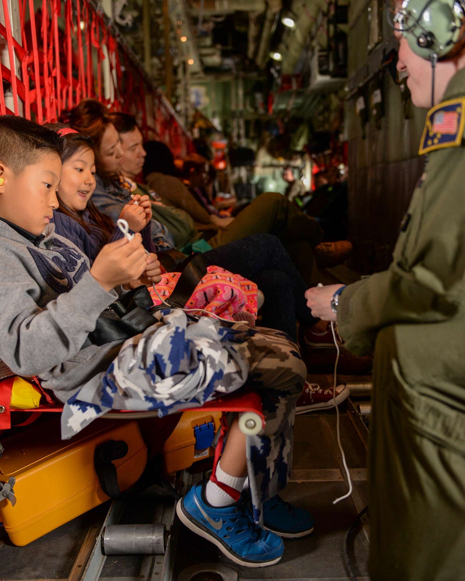 A crew member of a C-130 Hercules entertains military dependents with string tricks during a flight from Osan Air Base, Korea, to Yokota Air Base, Japan, May 15, 2015. The Alaska Air National Guard supported Yokota during a simulated noncombatant evacuation exercise, in part to test Yokota’s ability to integrate assets from other bases. (Airman 1st Class Elizabeth Baker/Released) 