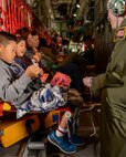 A crew member of a C-130 Hercules entertains military dependents with string tricks during a flight from Osan Air Base, Korea, to Yokota Air Base, Japan, May 15, 2015. The Alaska Air National Guard supported Yokota during a simulated noncombatant evacuation exercise, in part to test Yokota’s ability to integrate assets from other bases. (Airman 1st Class Elizabeth Baker/Released) 