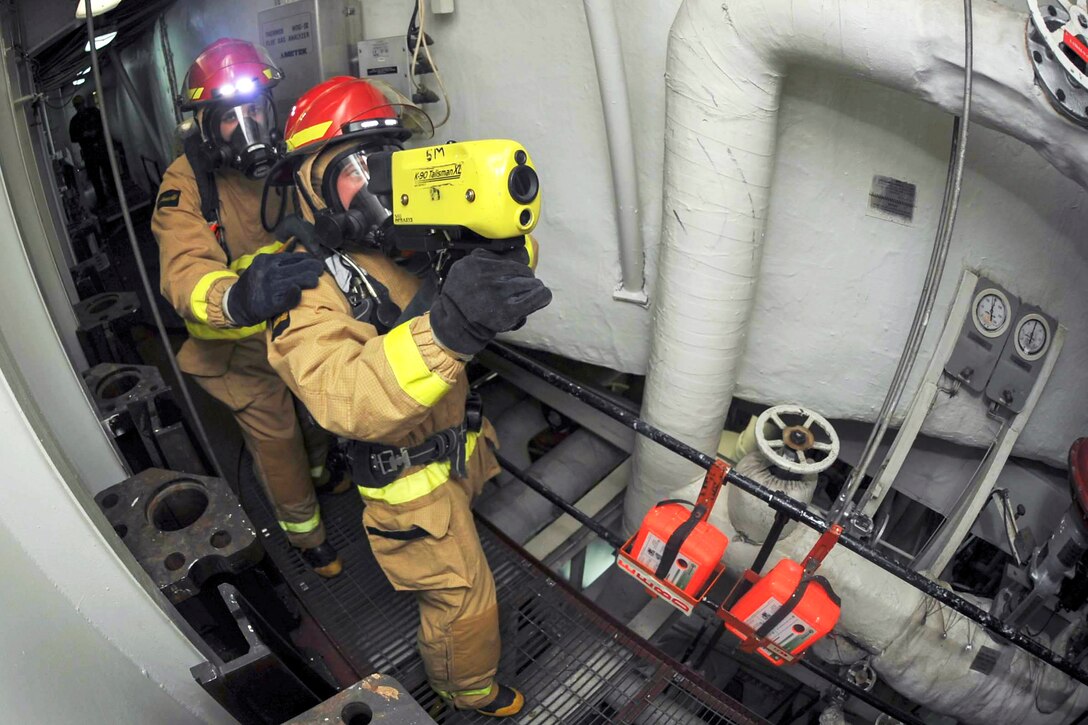 U.S. Navy Petty Officer 2nd Class Christian Karsemeyer, right, uses a navy firefighting thermal imager during a main space fire drill aboard the amphibious assault ship USS Boxer in the Pacific Ocean, May 7, 2015. Karsemeyer is a hull technician.