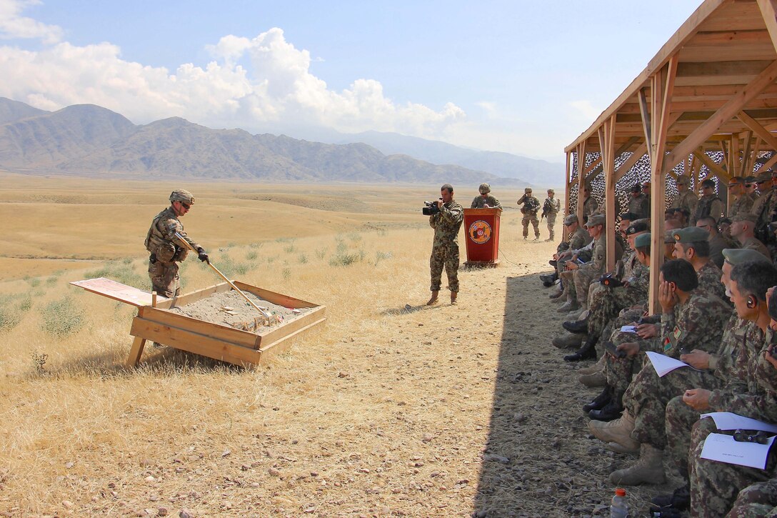 U.S. Army Capt. David Erck, left, points out the sequence of events of the combined arms live-fire exercise on a sand table before the start of the exercise at Tactical Base Gamberi in Laghman province, Afghanistan, May 13, 2015. Erck is an explosive ordnance disposal officer assigned to Train Advise Assist Command East.