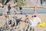 Air Force Chief Master Sgt. Don Kuehl (left), Air Force Staff Sgt. Bennett Groth and an interpreter talk with three farmers planting alfalfa at the proposed site of a demonstration farm near the Sarkani District Center in Kunar province, Nov. 22.